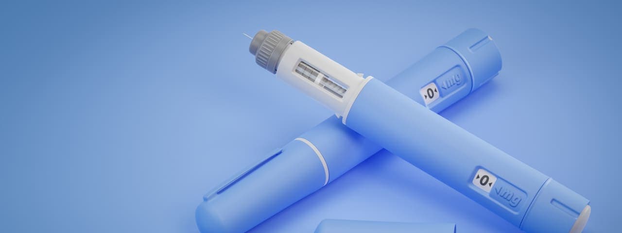 Two Ozempic syringes against a blue background